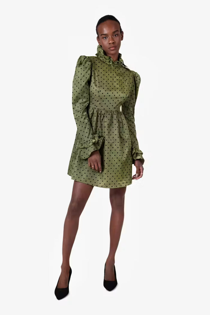Woman wearing a green polka dot dress on a white background