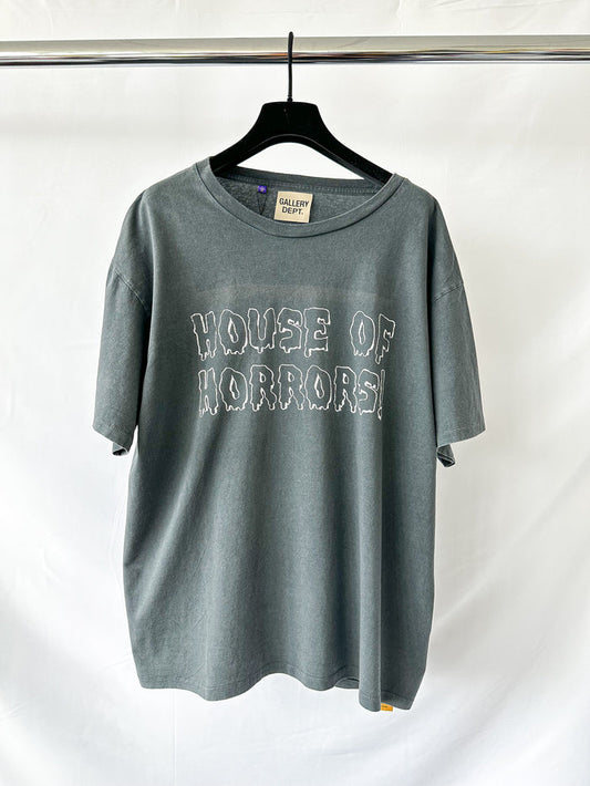 Gray t-shirt with 'HOUSE OF HORRORS' text on a hanger against a white background