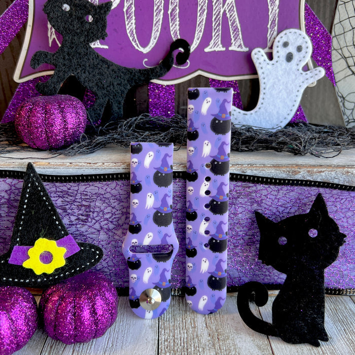 Ghostly Whisker's Fitbit Versa 1/2 band shown as two strap halves standing upright with glitter pumpkins and a felt witch hat.