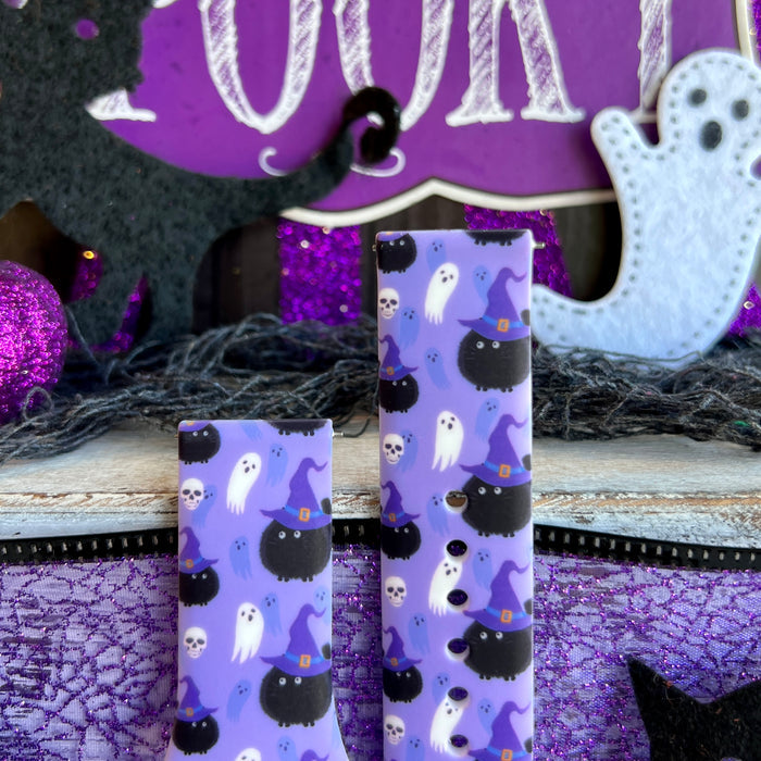 Ghostly Whisker's Fitbit Versa 1/2 band straps side by side showing white ghosts on one and black cats on the other over lavender.