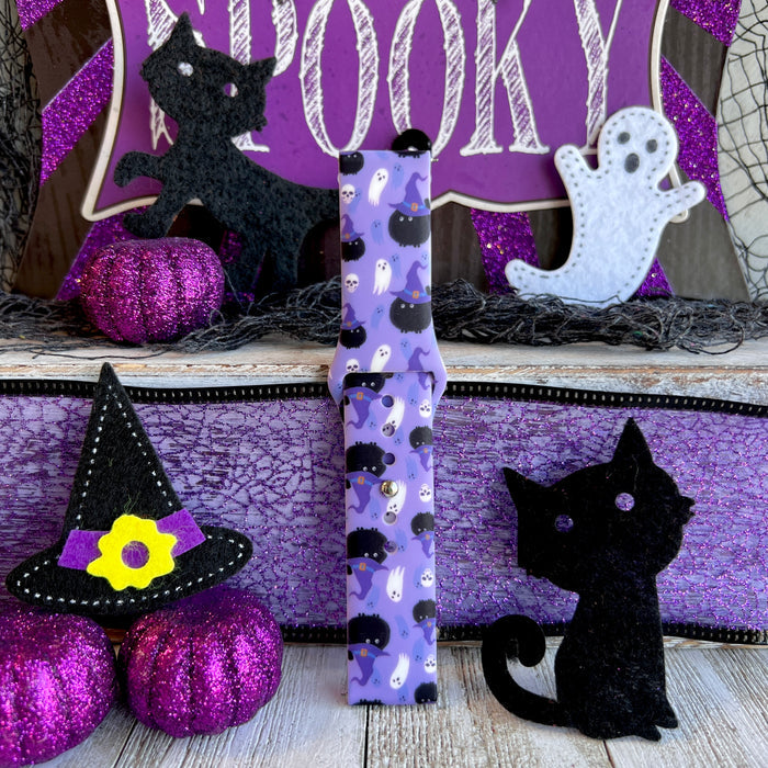 Single Ghostly Whisker's Fitbit Versa 1/2 band strap standing to show the black cat and mini skull print on lavender silicone.