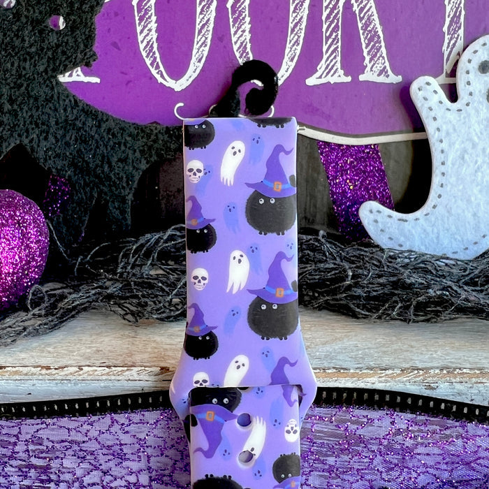 Close-up of the Ghostly Whisker's Fitbit Versa 1/2 band showing white ghosts in purple witch hats across the lavender strap.