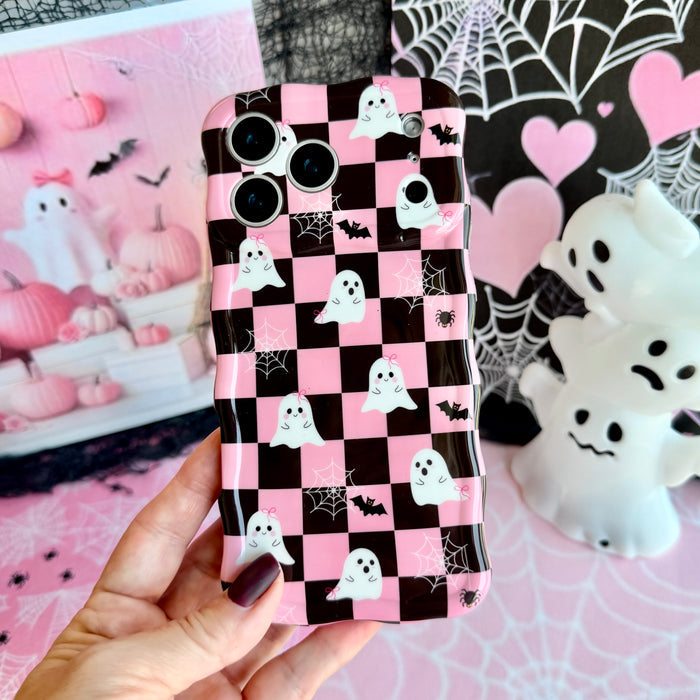 Hand holding the Hey Boo, Looking Cute Wavy Luxe MagSafe iPhone case, pink and black checkerboard with white ghosts, black bats and white spiderwebs.