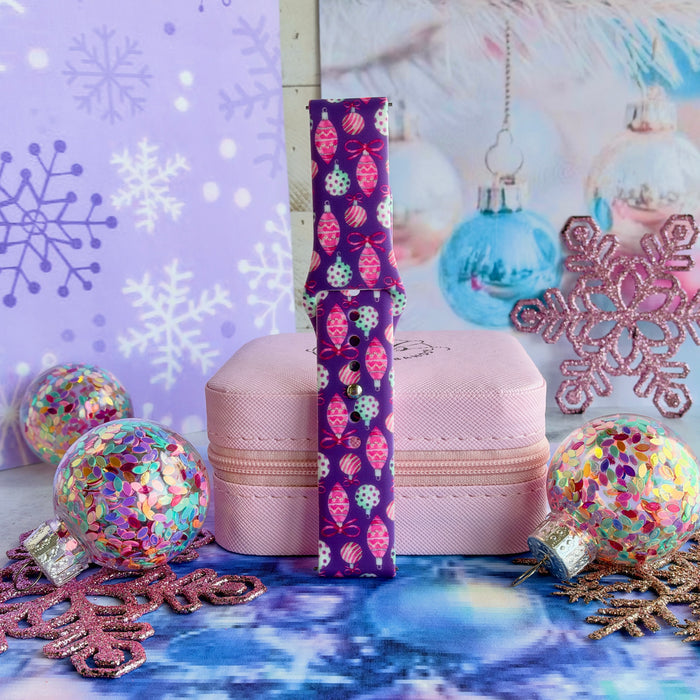 Single Just One More Ornament Samsung watch band strap standing on a pink jewelry box with aqua and pink glass ornaments behind