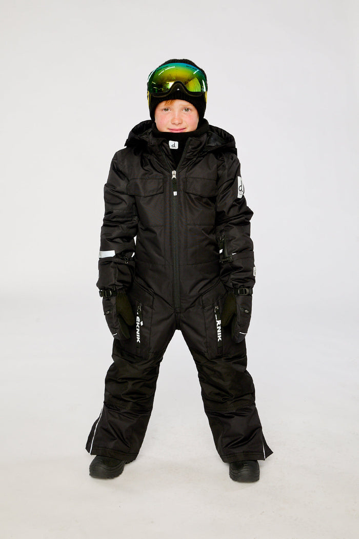 Child wearing the black Deux par Deux TEKNIK one-piece snowsuit with ski goggles, front view