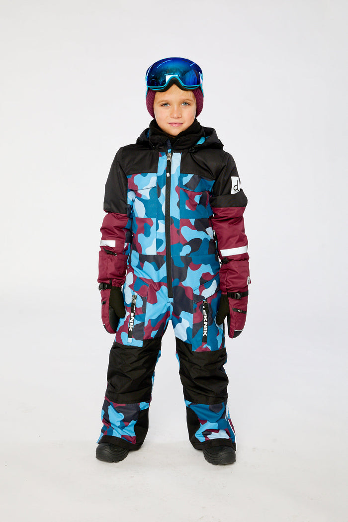 Child wearing the blue and red camouflage Deux par Deux TEKNIK one-piece snowsuit, front view