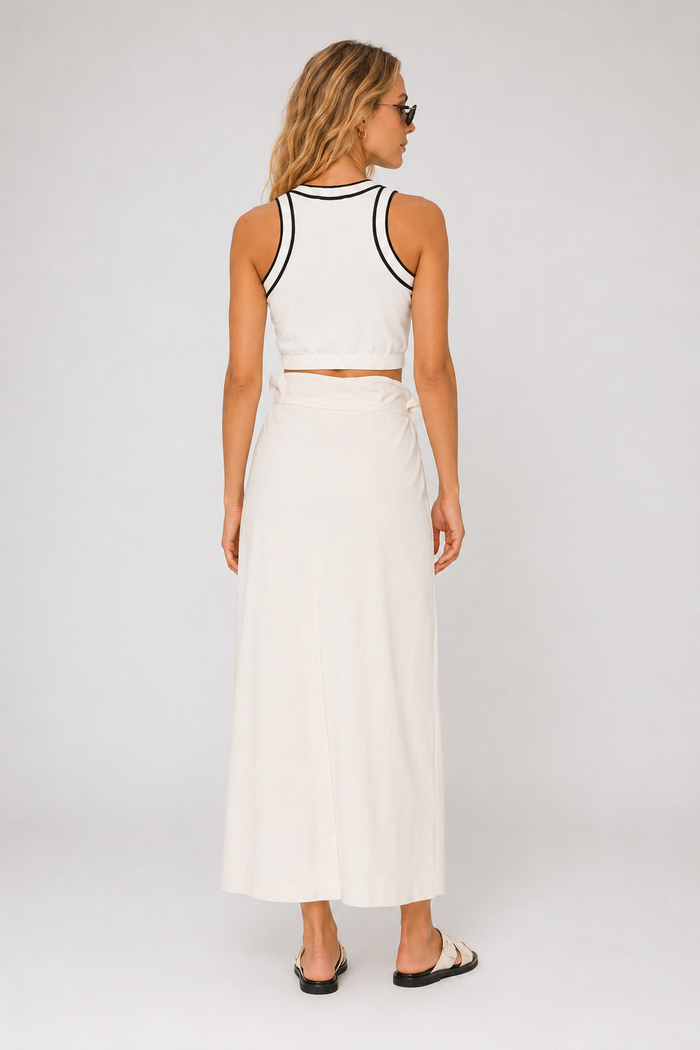 Woman wearing a max mara white sleeveless top and long skirt with black trim on a plain background