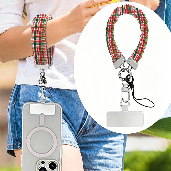 Merry Little Plaid scrunchie phone strap worn on the wrist with an iPhone hanging from it, plus close-up of the strap and phone tab