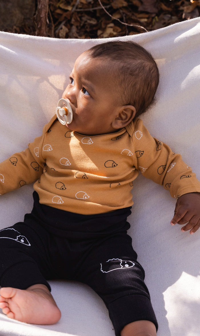 Baby wearing the evolutive pants, black and brown with hedgehog details, view 2