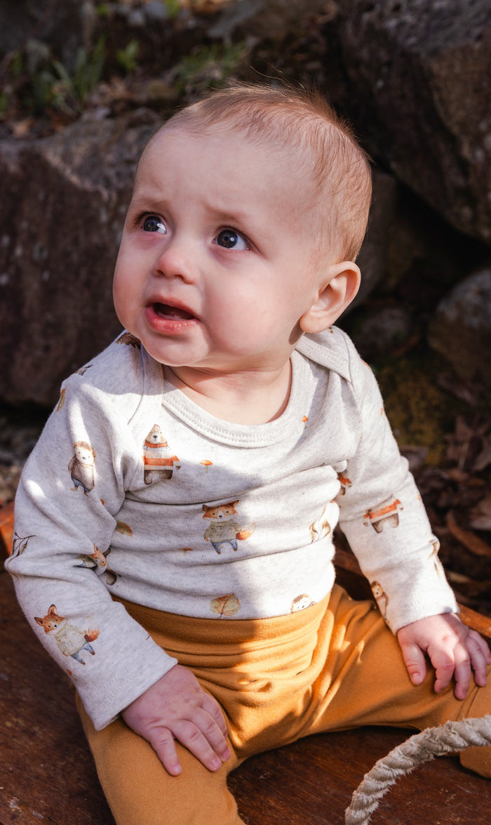 Baby wearing the Deux par Deux organic cotton onesie in beige woodland animal print, view 2