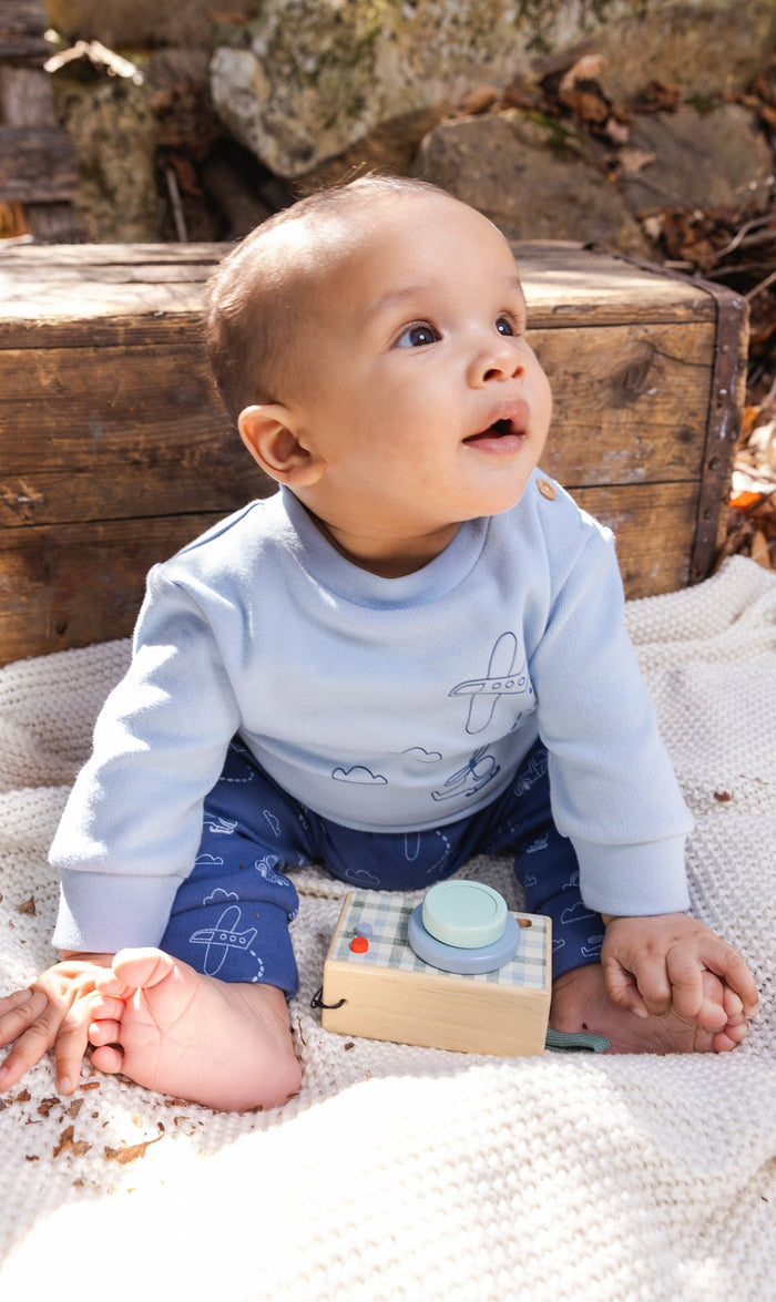 Baby wearing the Deux par Deux set with sky blue top and deeper blue airplane and cloud print pants, view 2