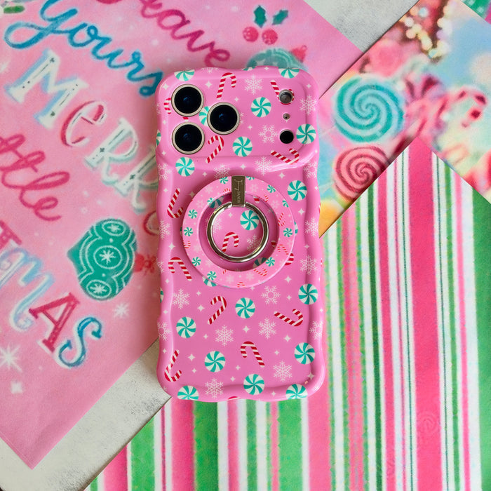 Peppermint Cutie pink peppermint MagSafe grip ring snapped onto the matching iPhone case, on a Merry Little Christmas sign