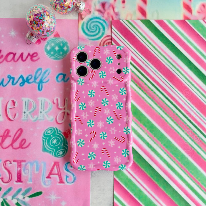 Peppermint Cutie iPhone case lying on pink, green and white candy stripe paper beside a Have Yourself a Merry Little Christmas sign