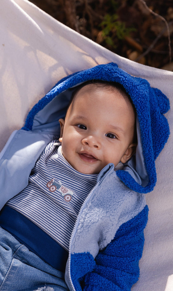 Baby boy wearing the Deux par Deux blue sherpa hooded jacket with bear ears, lifestyle photo