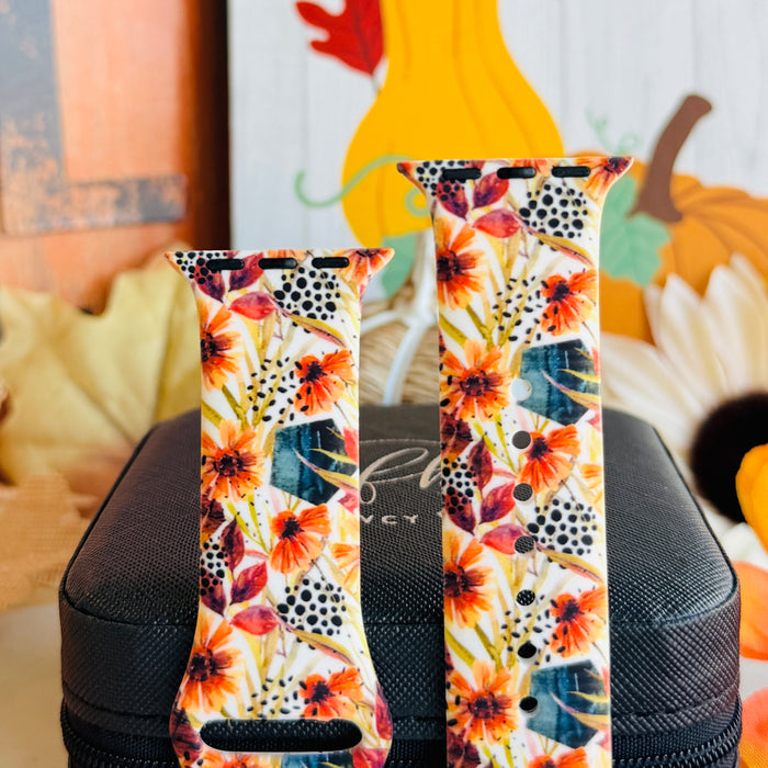 Both sizes of the Sienna Petals Apple Watch band standing side by side, close view of the rust flowers, deep teal foliage and black dot clusters.