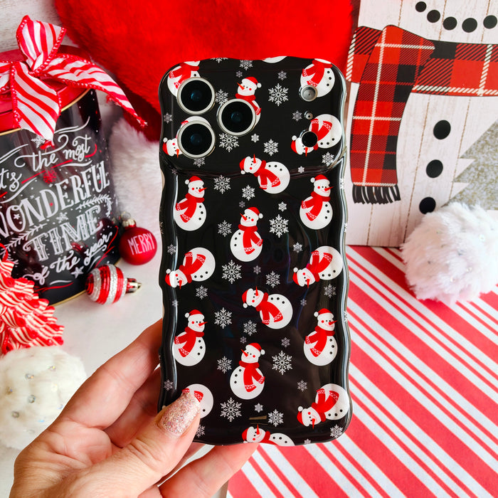 Hand holding the Snowman Wavy Luxe MagSafe iPhone case, white snowmen in red scarves and Santa hats with snowflakes on black