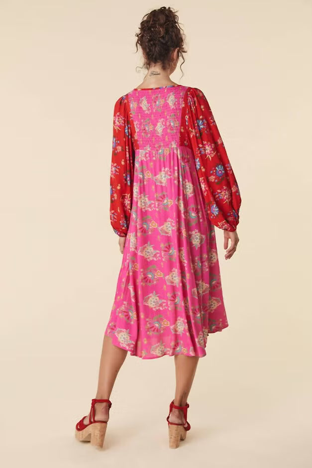 Woman wearing a pink floral dress with long sleeves on a beige background