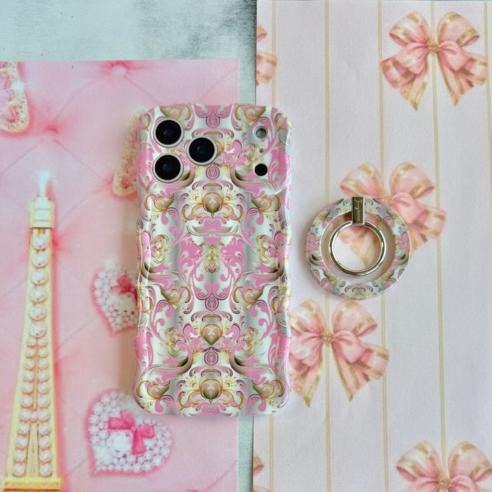 The Pink Heiress baroque MagSafe grip ring shown beside its matching pink and gold iPhone case on a coquette flat lay with pink bows and a pearl heart.