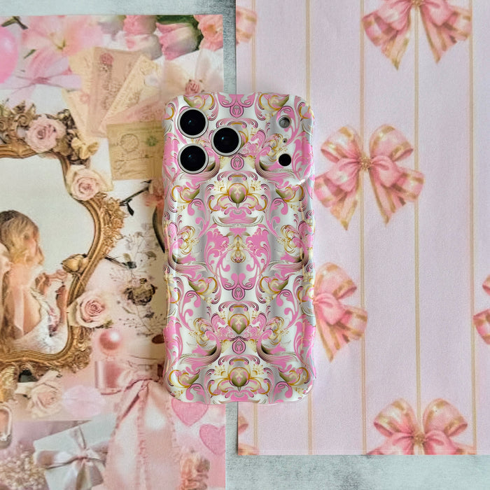 The Pink Heiress pink and gold damask MagSafe iPhone case styled on pink bow paper with a vintage cherub print, showing the scrollwork and the sculpted wavy border.