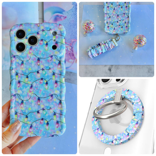 Twinkle All The Way iPhone Matching Set - pastel blue MagSafe case with pink, violet and aqua Christmas string lights, matching Hold It Fancy grip ring and scrunchie phone wrist strap from Fancy Bands