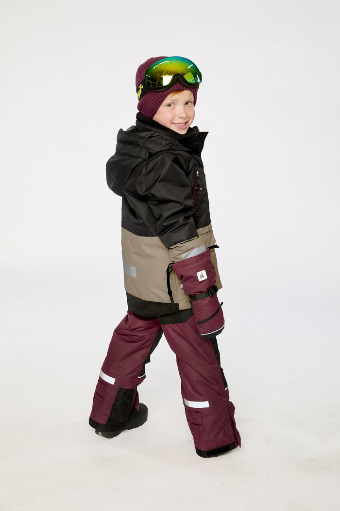 Child walking in the black, beige and burgundy Deux par Deux TEKNIK two-piece snowsuit
