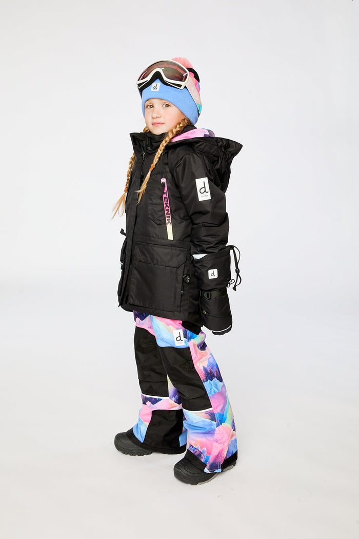Deux par Deux girls' Teknik snowsuit, black jacket and pink-blue mountain print pants – on a child model, side view