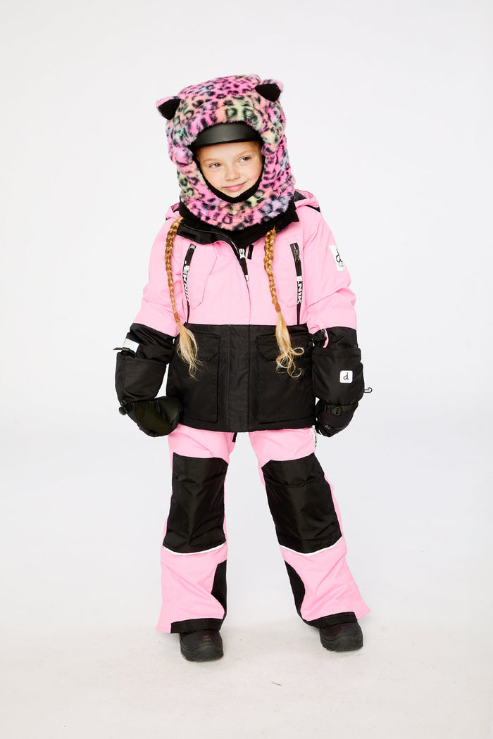 Child wearing the pink and black Deux par Deux TEKNIK two-piece snowsuit, standing front view