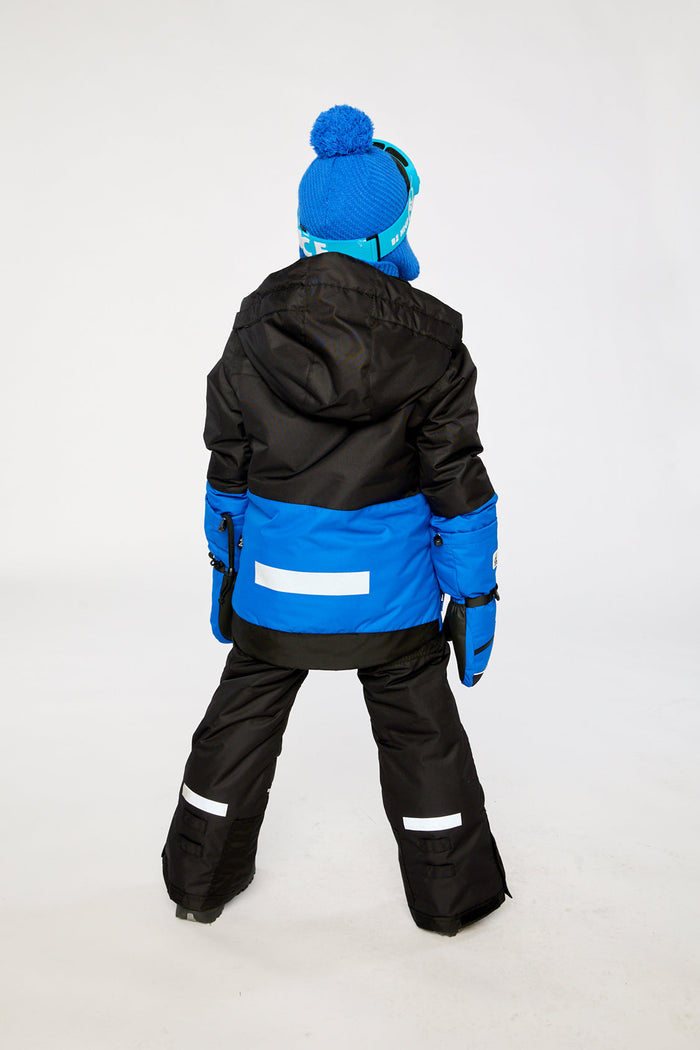 Child wearing the black and royal blue Deux par Deux TEKNIK two-piece snowsuit, back view
