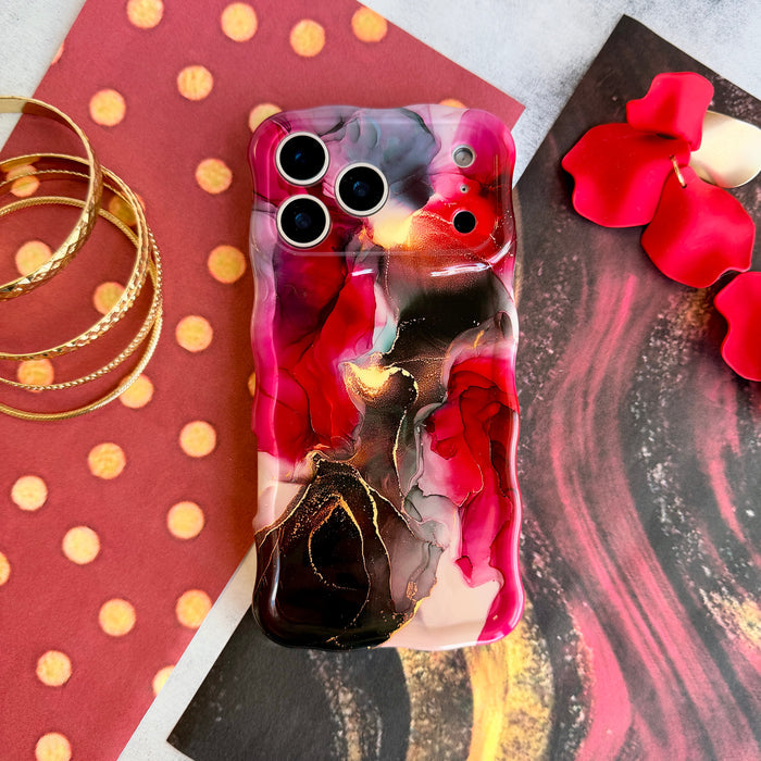 The Velvet Vixen red, black and gold marble MagSafe iPhone case styled on red polka dot paper with stacked gold bangles and scattered rose petals.